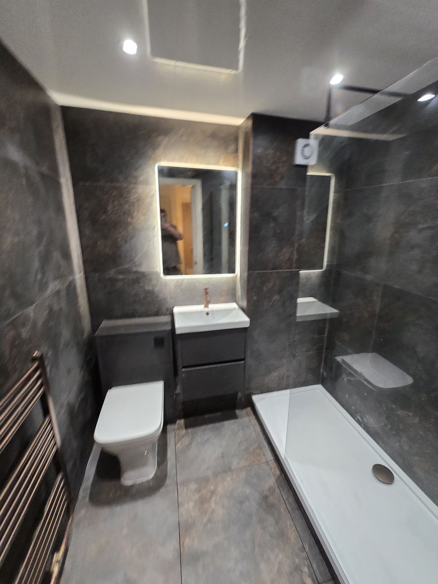 Dark slate bathroom with LED mirror and walk-in shower