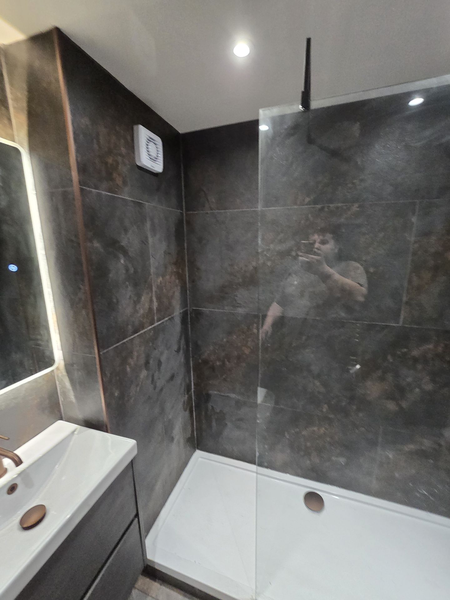 Modern bathroom shower enclosure with dark stone tiles