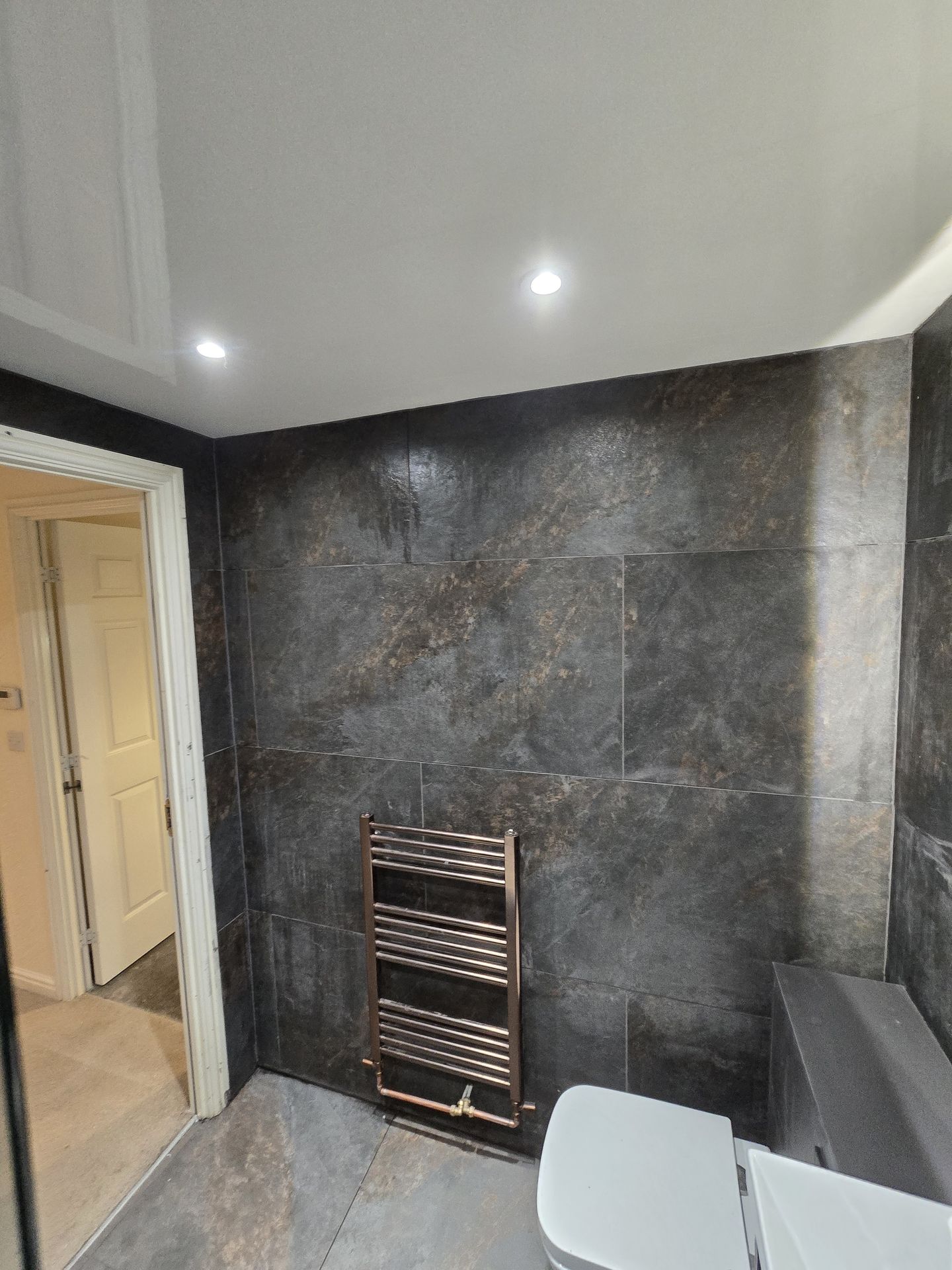 Bathroom radiator installation with dark stone wall tiles