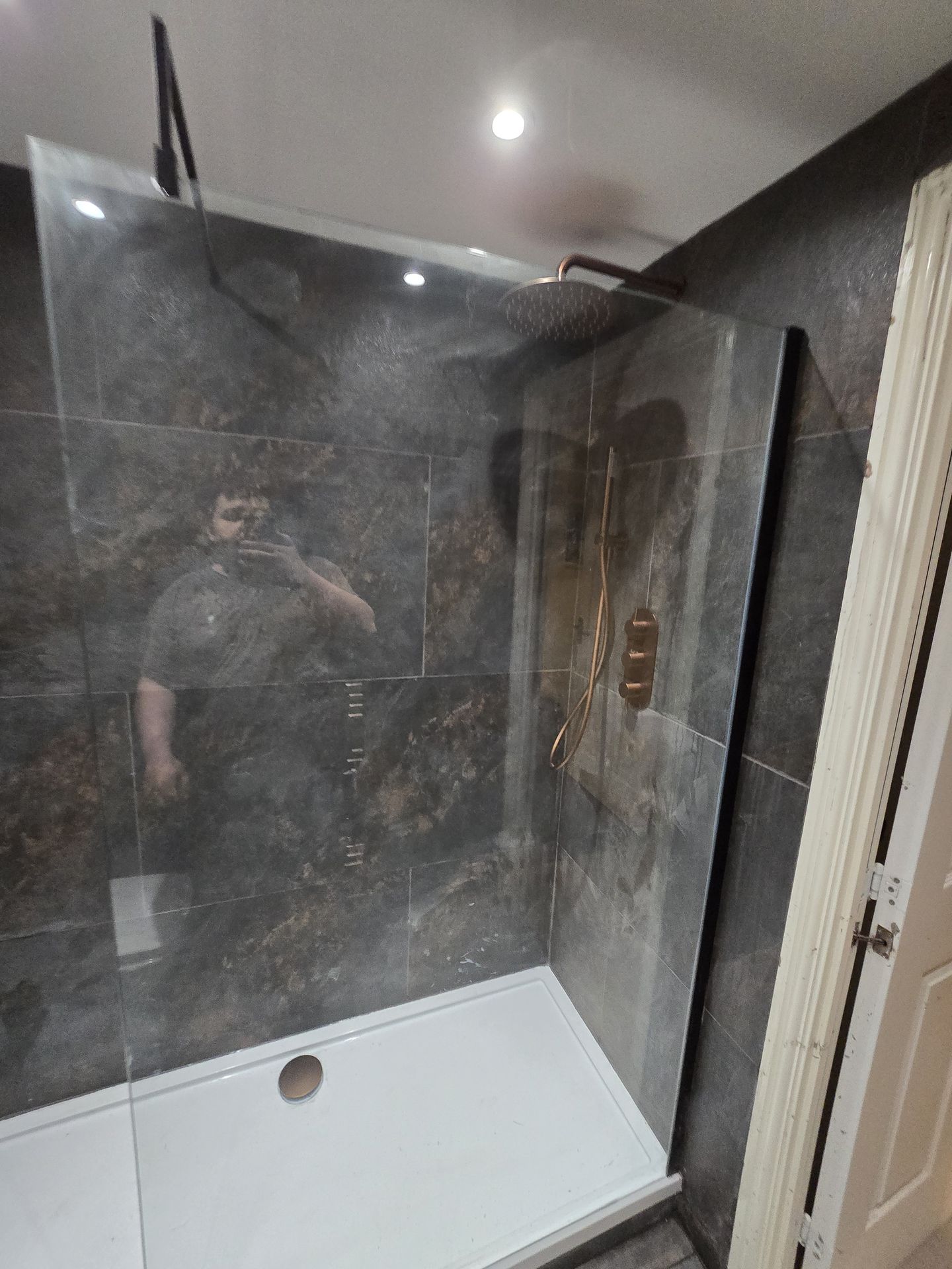 Walk-in shower with copper fixtures and glass screen