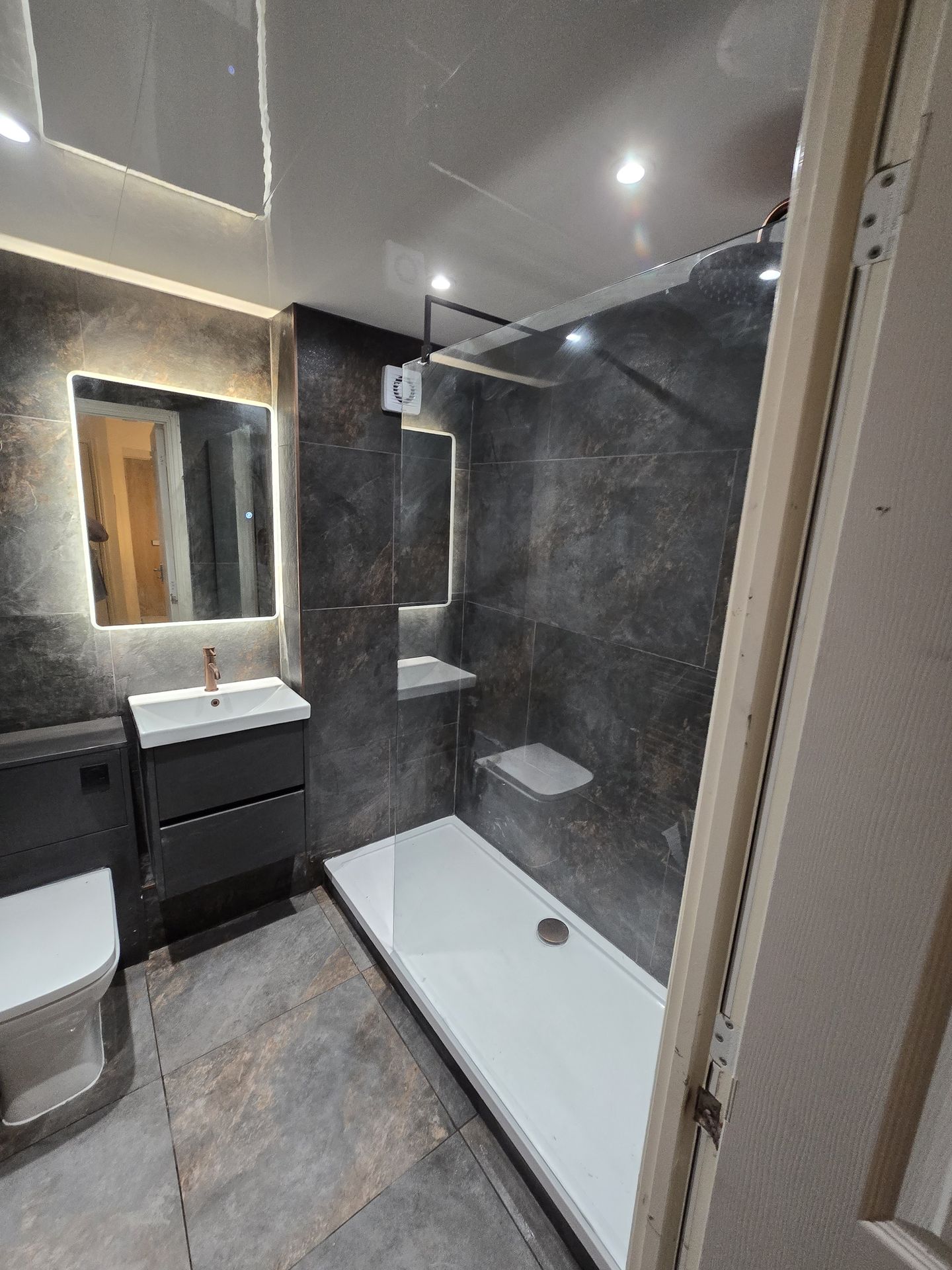 Full bathroom renovation with dark tiles and modern fixtures