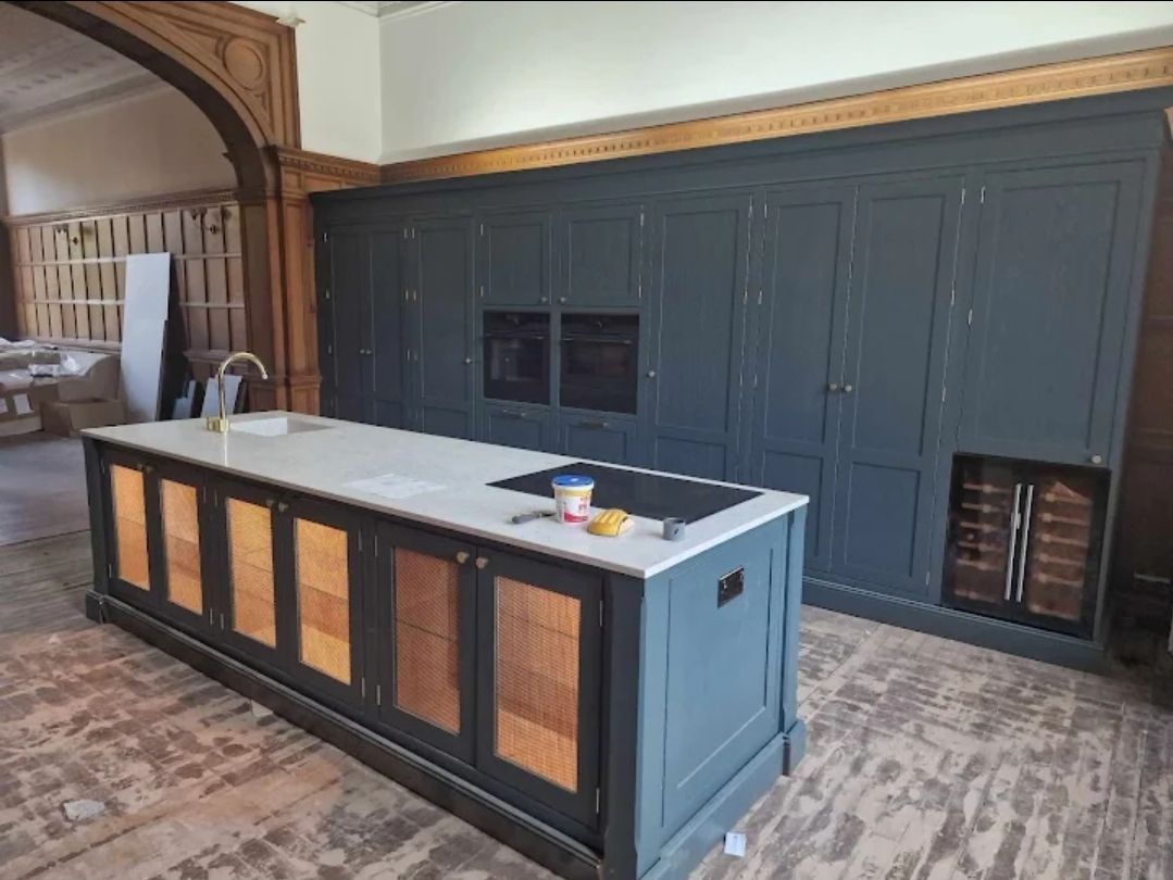 Teal kitchen cabinets with marble worktop and wine cooler